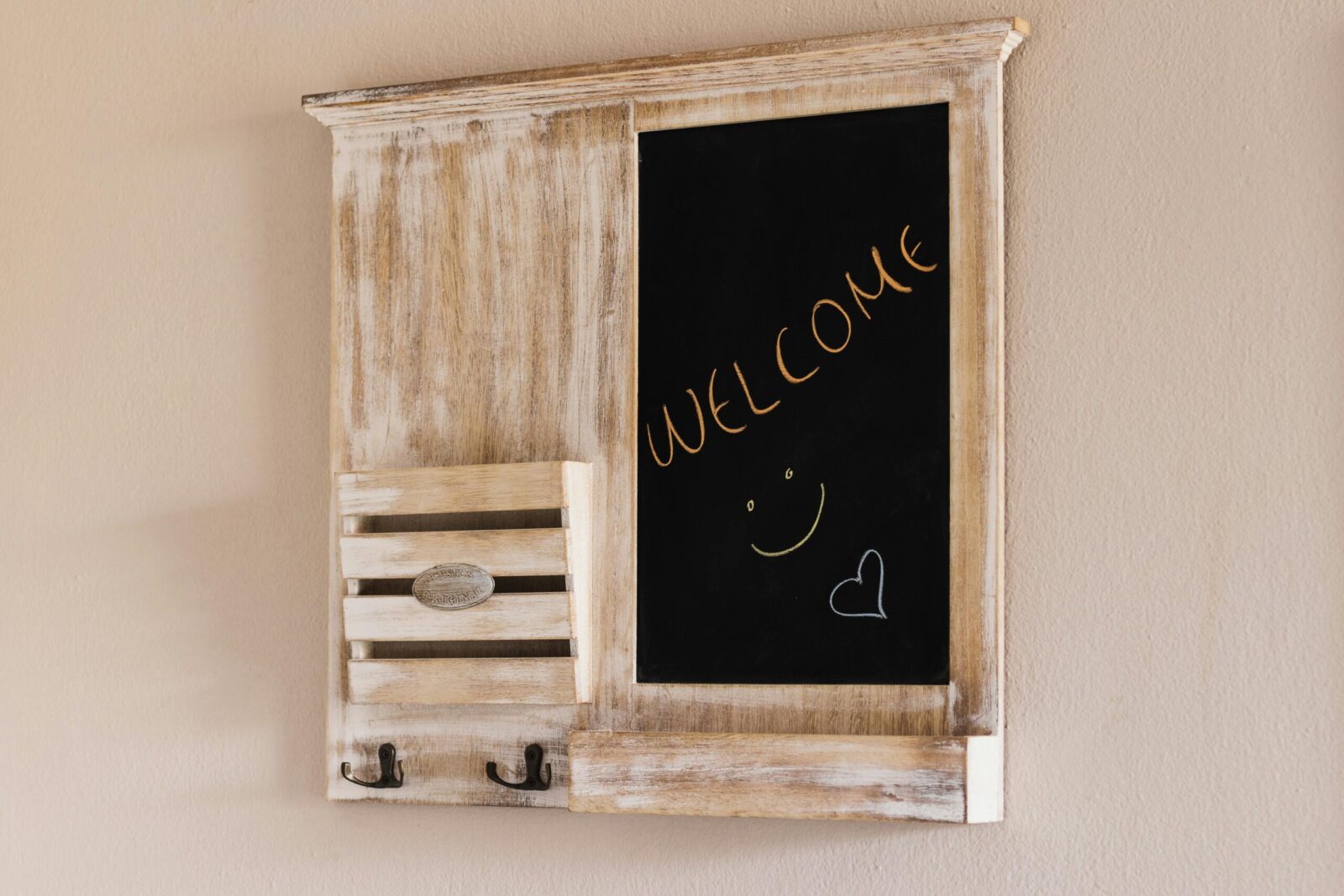 Decorative rustic chalkboard with 'Welcome' text on a beige wall, ideal for home decor.