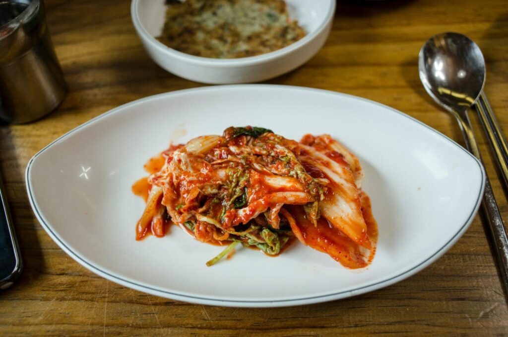 Vibrant Korean kimchi served on a white ceramic plate, showcasing authentic flavors.