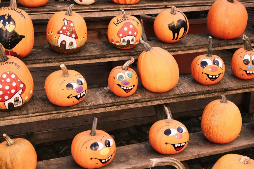 Playful and painted pumpkins with autumnal designs on wooden steps, perfect for Halloween.