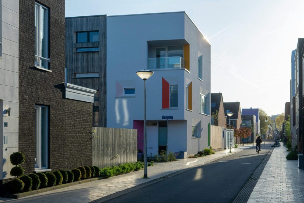 Contemporary homes line a quiet street in Leiden, Netherlands, with a cyclist passing by.