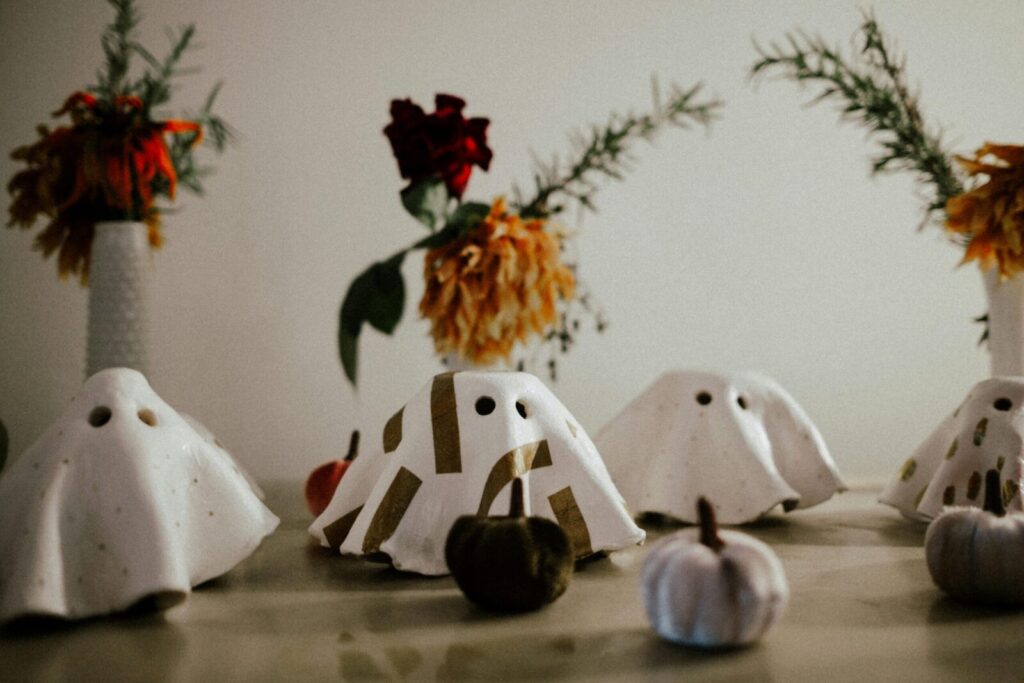Charming Halloween decor with ghost figures surrounded by pumpkins and floral vases, setting a festive mood.