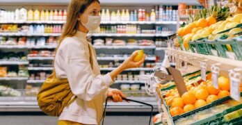 A woman wearing a face mask shops for fruits in a supermarket during a pandemic.