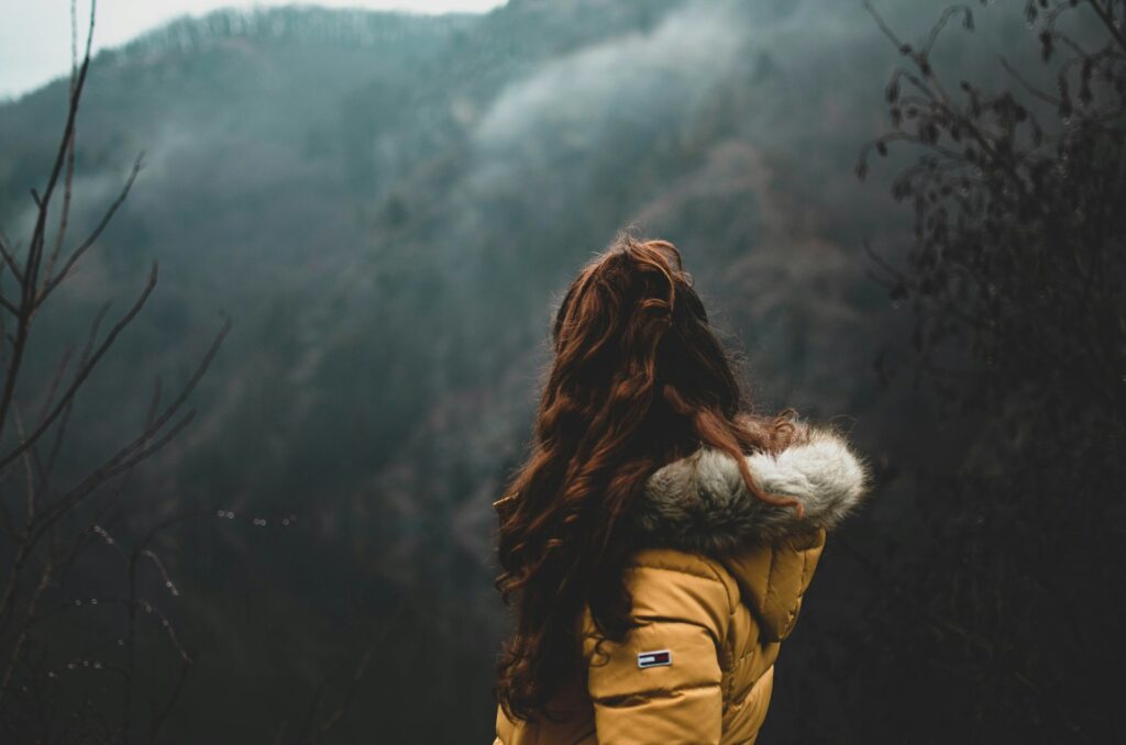 woman in brown parka jacket standing on snow covered ground