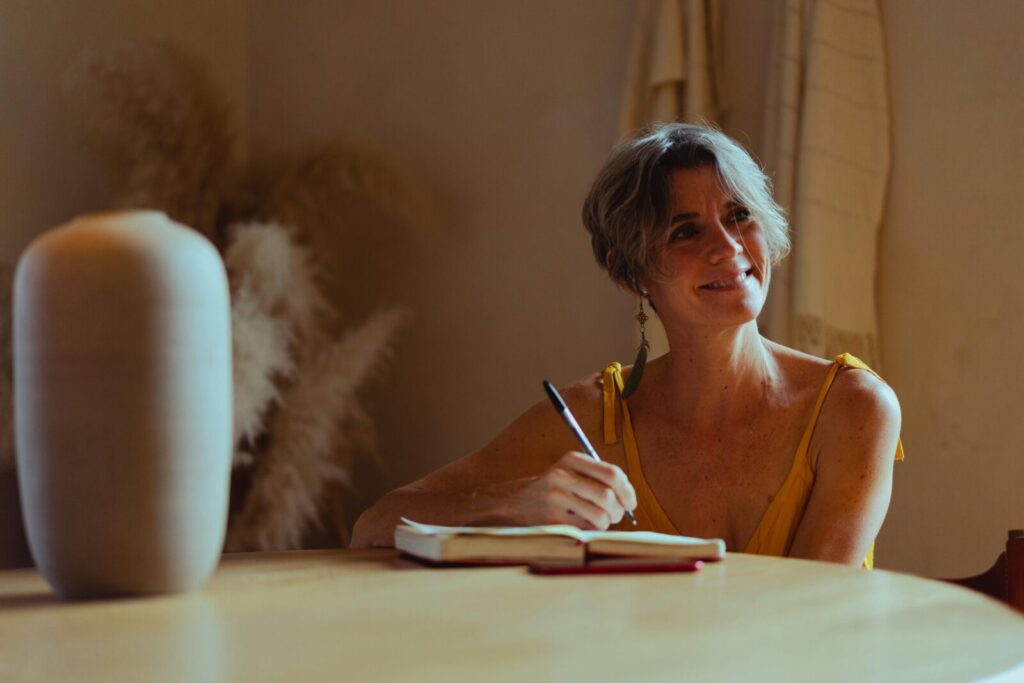 A senior woman is writing in her journal at home, enjoying a peaceful and reflective moment.