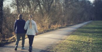 woman in white jacket and black pants walking on road during daytime