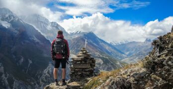 man standing on top of mountain beside cairn stones