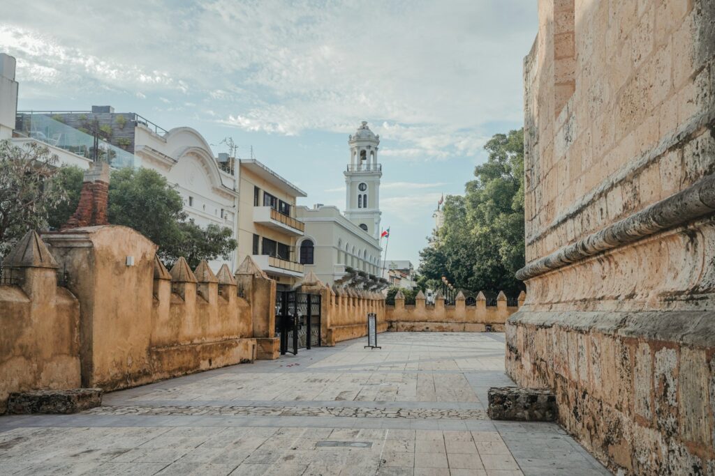 a narrow street with a clock tower in the background