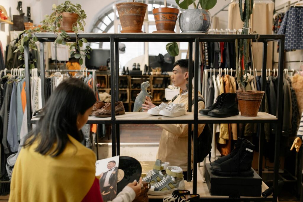 People browsing and selecting items in a stylish vintage clothing shop interior.