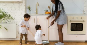 A mother and her two children cleaning together in a bright, modern kitchen.