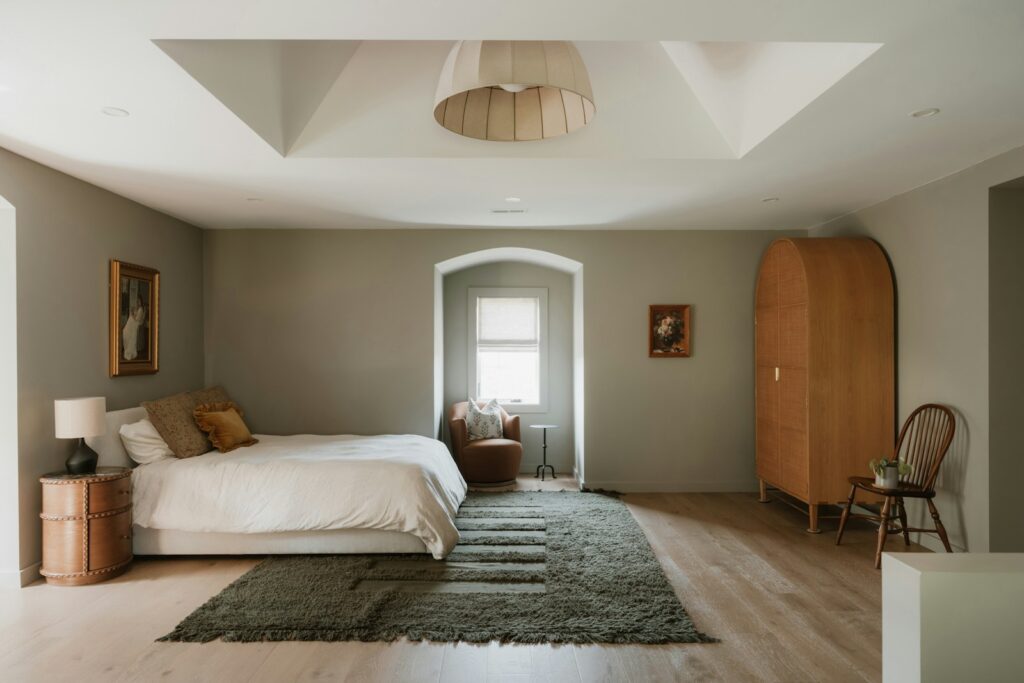 A neutral bedroom with a large bed and wooden wardrobe.