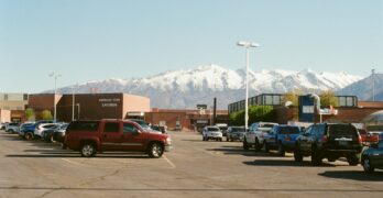 Parking lot of a building with snowy mountains in the background.