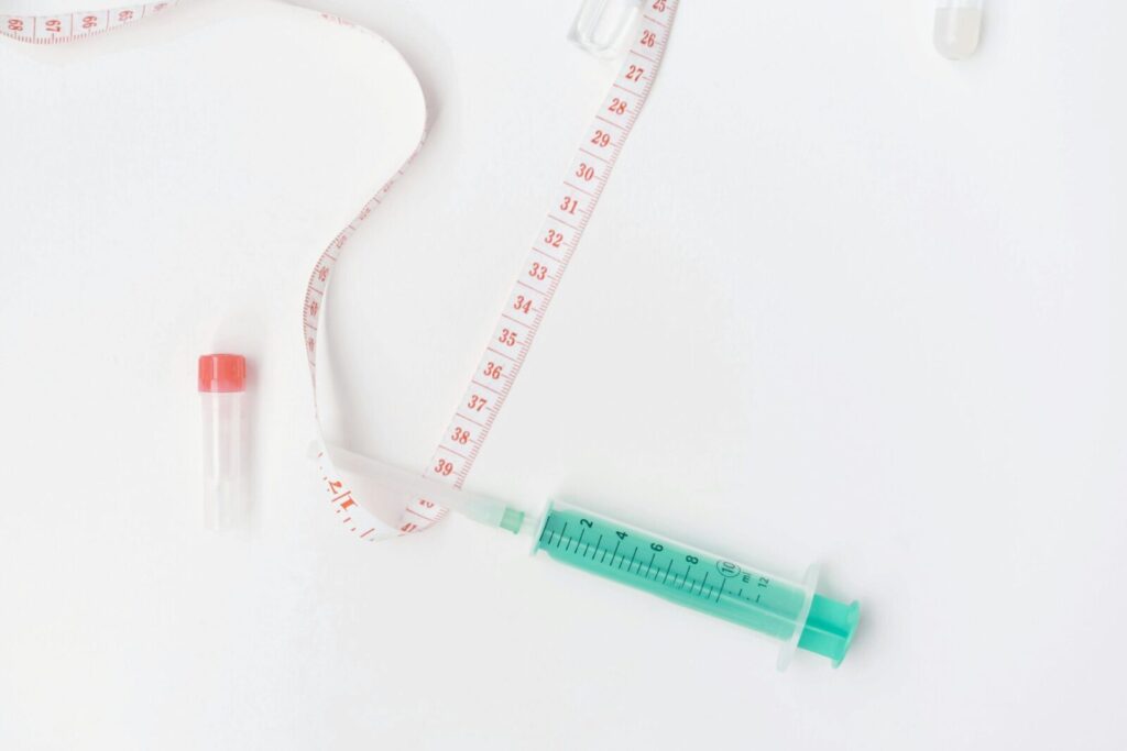 Flat lay of medical supplies with tape measure and syringe on white background, symbolizing healthcare.