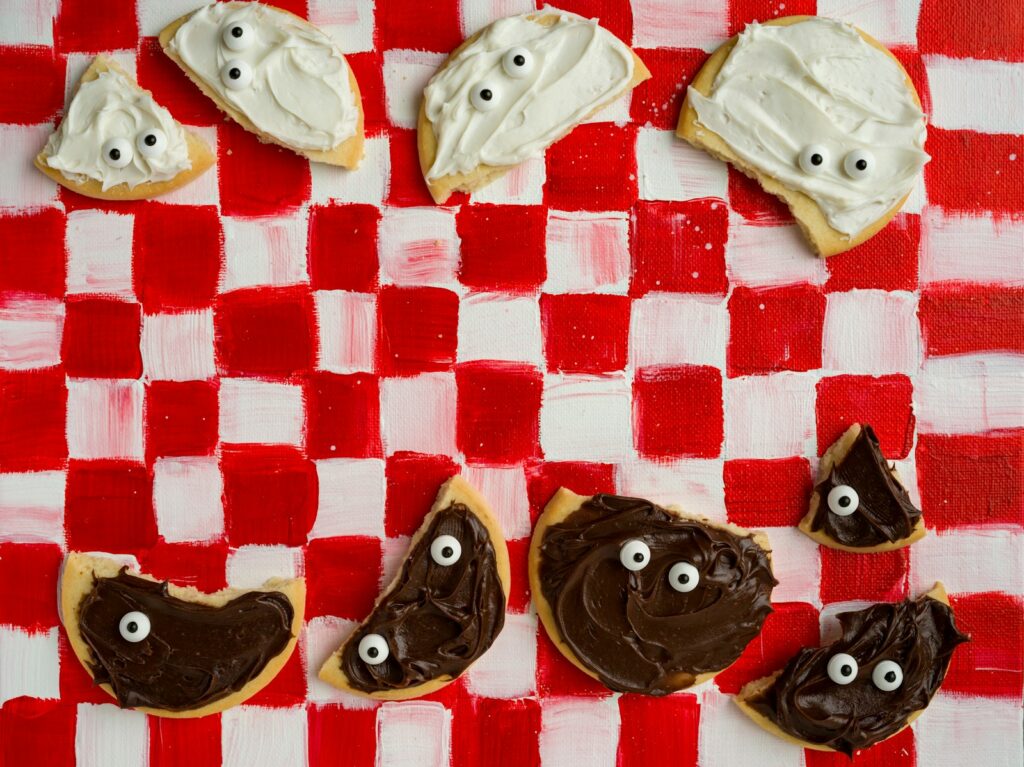 a red and white checkered table cloth with cookies decorated to look like ghost faces