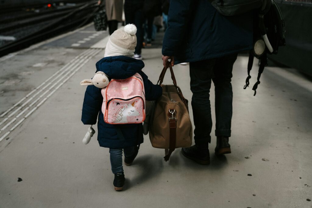 A child walks with a person holding luggage.