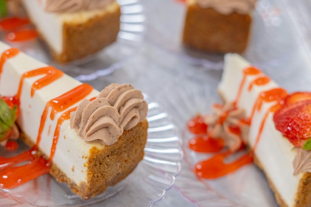 Cheesecake slices with topping and a strawberry drizzle.