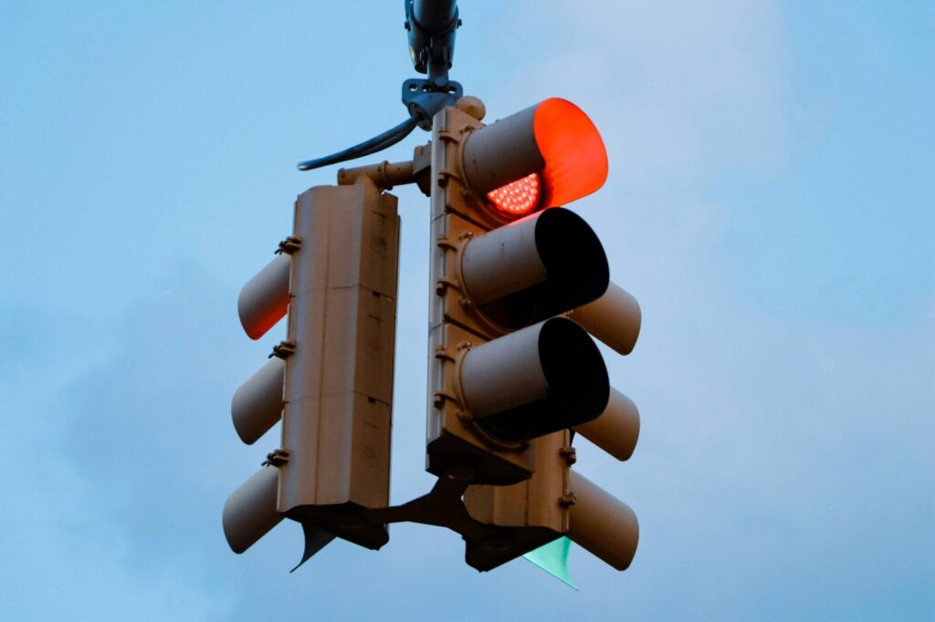Close-up of a red traffic light signaling stop against a clear blue sky.