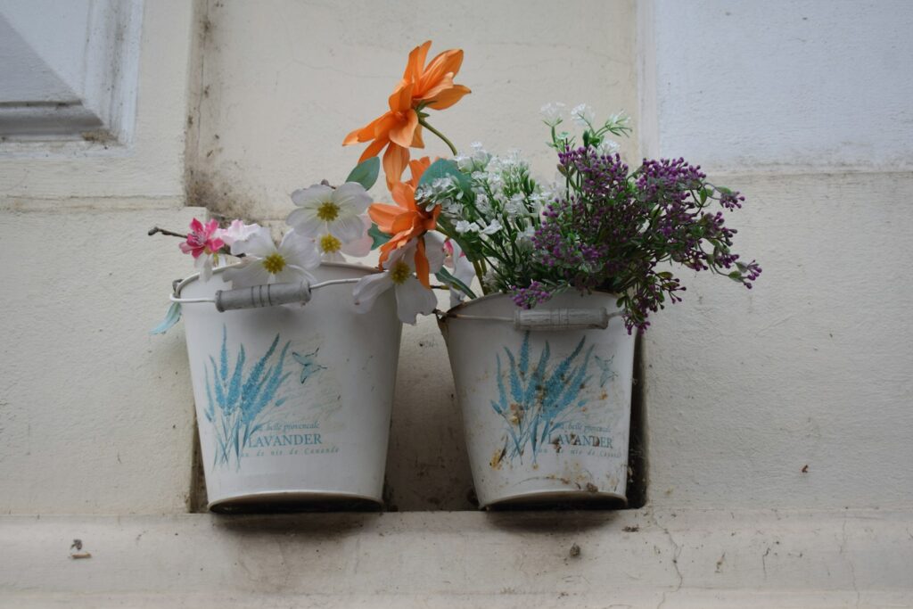Two buckets of artificial flowers on windowsill