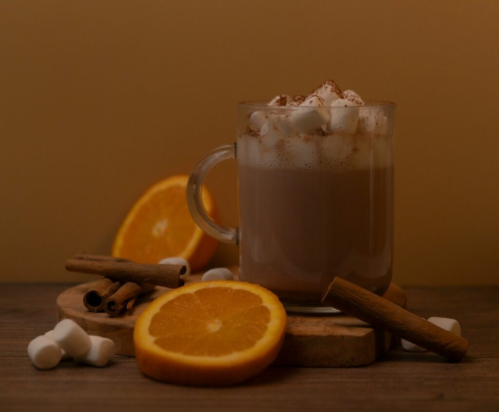 A cup of hot chocolate with cinnamon and an orange slice
