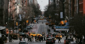 Vibrant New York City street bustling with people, taxis, and skyscrapers in urban daylight.