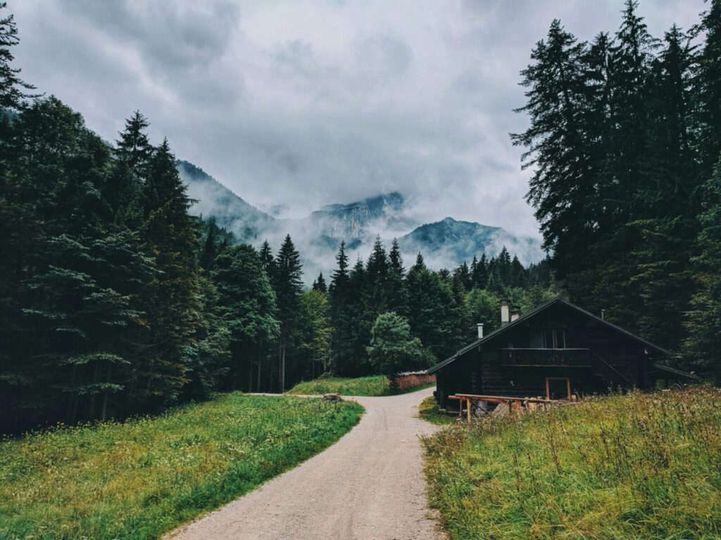 A picturesque cabin surrounded by misty forests and mountains in the German Alps.