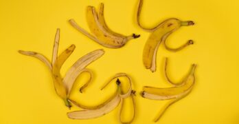 Artistic arrangement of banana peels on a vibrant yellow background, top view.