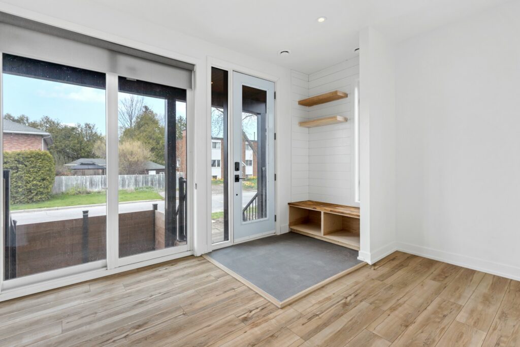 a room with a wood floor and a glass door with a rug and a wood floor with a