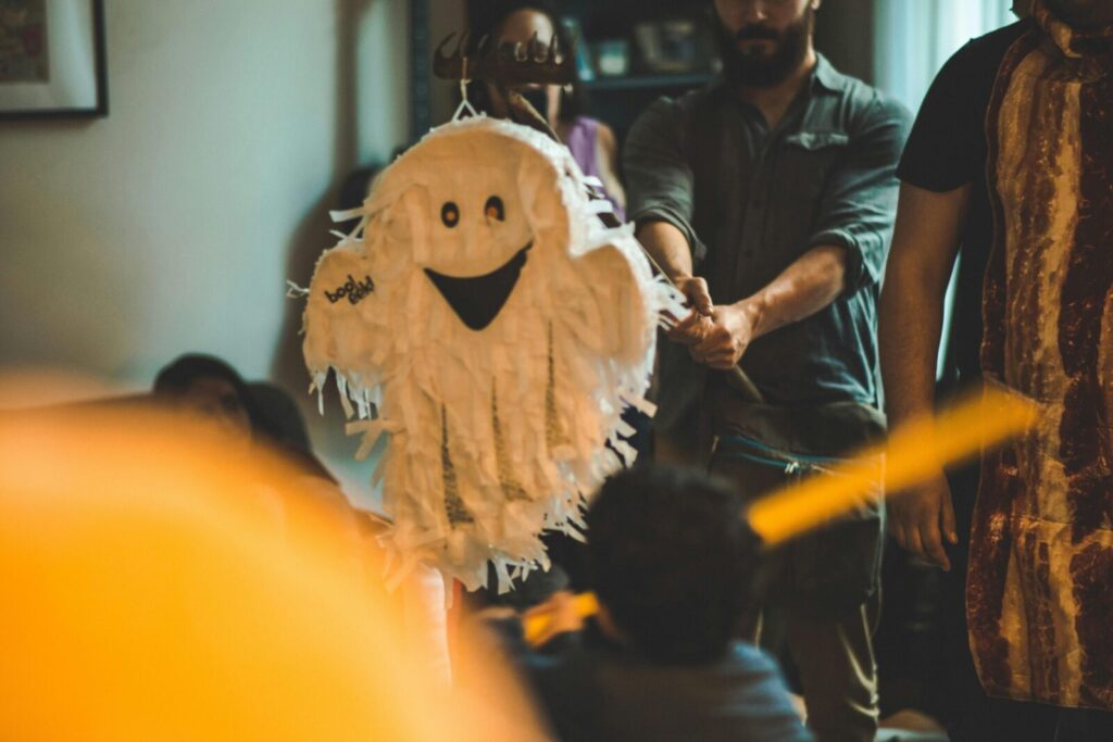 A festive Halloween party with guests enjoying a ghost-shaped pinata indoors.