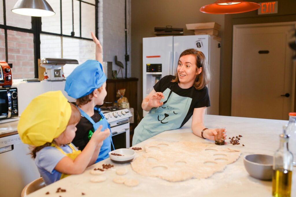 A joyful cooking lesson with kids baking cookies under adult supervision in a modern kitchen setting.