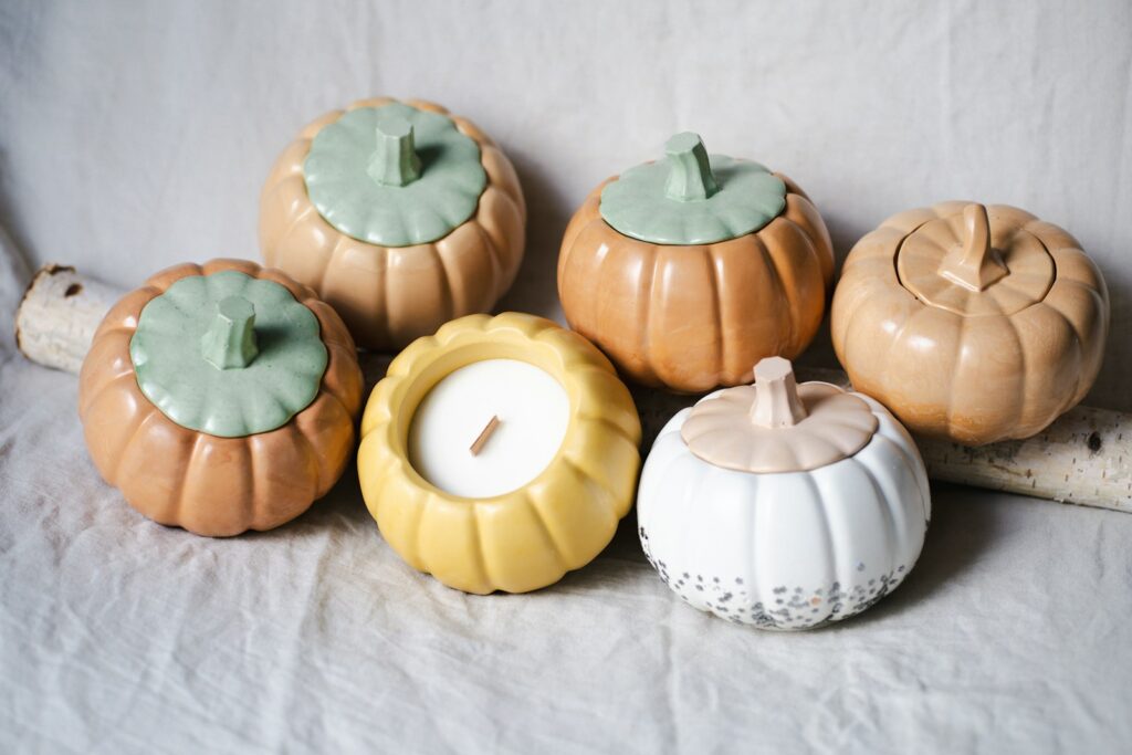 Pumpkin-shaped candle holders are displayed on a white surface.