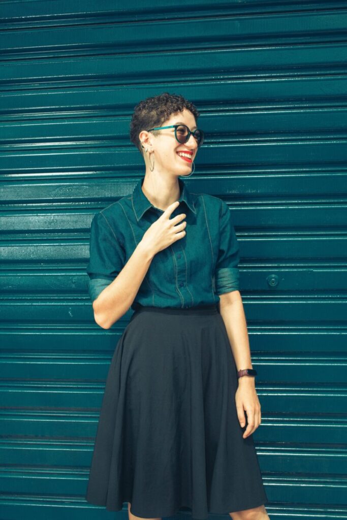 Fashionable woman with eyeglasses smiling against blue shutter background.