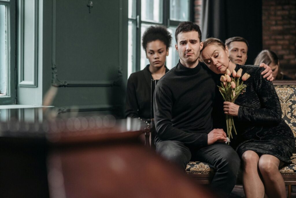 Family members in mourning sit together during a funeral, expressing sorrow and support.