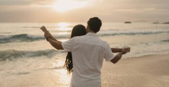 A man and a woman are standing on the beach