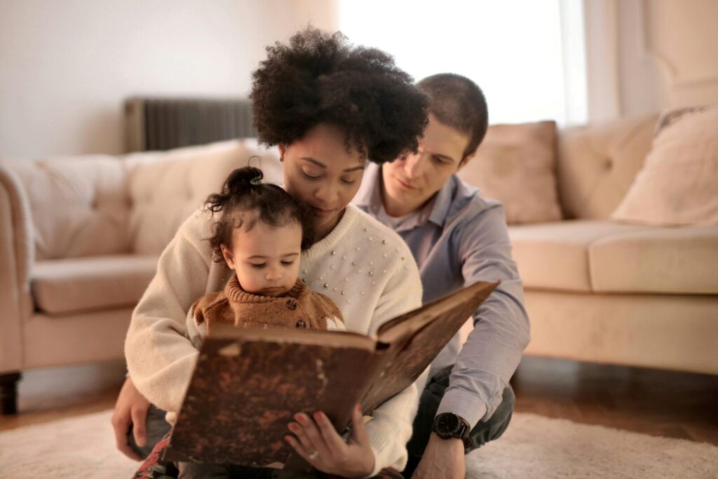 Mother, father, and child enjoying a storybook together in their cozy living room.