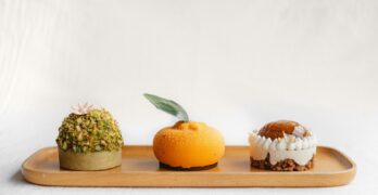 a wooden tray topped with three desserts on top of it