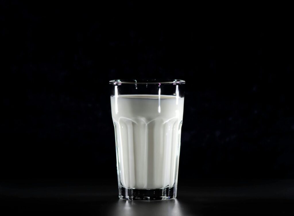 A glass of fresh milk against a black background, emphasizing simplicity and nutrition.