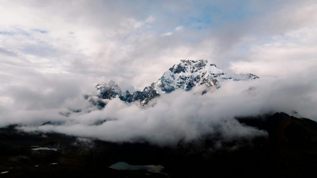 Breathtaking view of snowcapped Andes mountains peeking through clouds in Cusco, Peru.