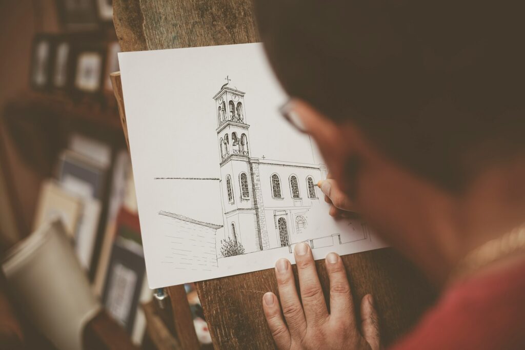 a person holding a piece of paper with a drawing of a church on it