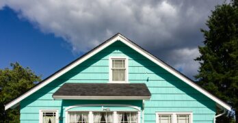 a blue house with white windows and a black roof