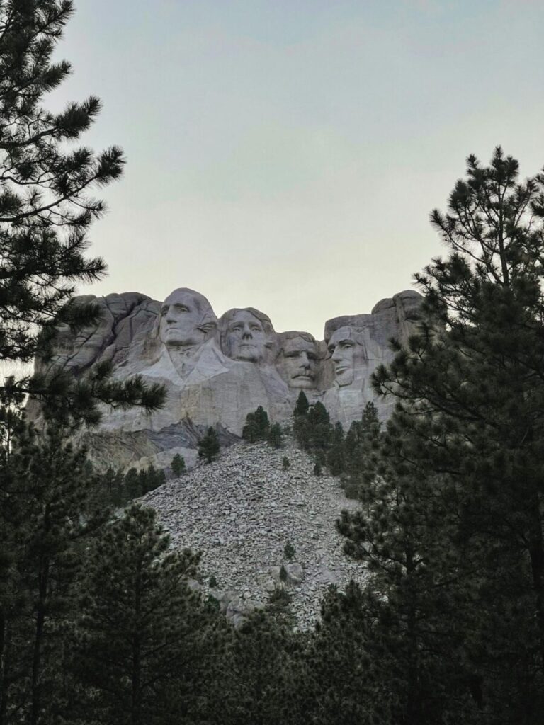 View of Mount Rushmore through pine trees in Keystone, South Dakota.