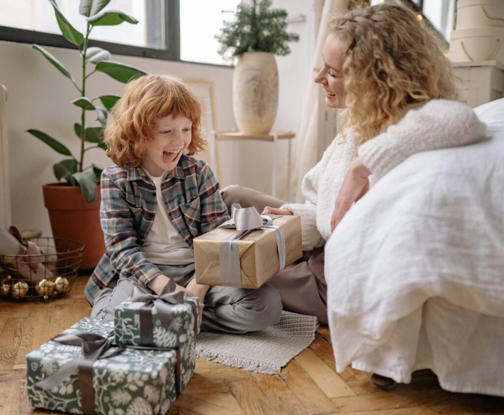 A mother and child exchanging gifts in a cozy home setting, showcasing joy and togetherness.