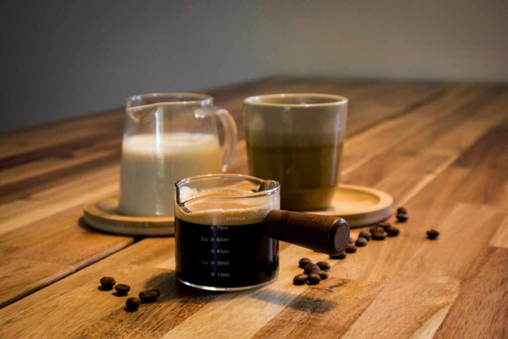 An artistic arrangement of espresso with milk and coffee beans on a wooden table.