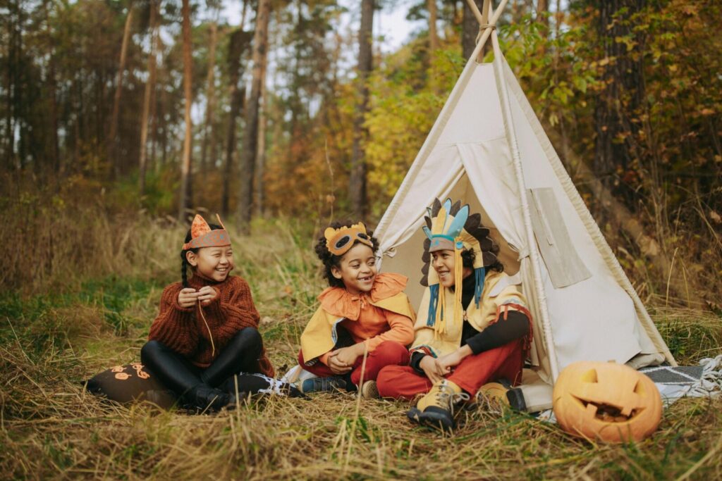Kids enjoy a fall camping trip in costumes with a carved pumpkin.