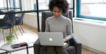 a woman sitting in a chair using a laptop computer