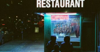 People admire the food display in a restaurant window.