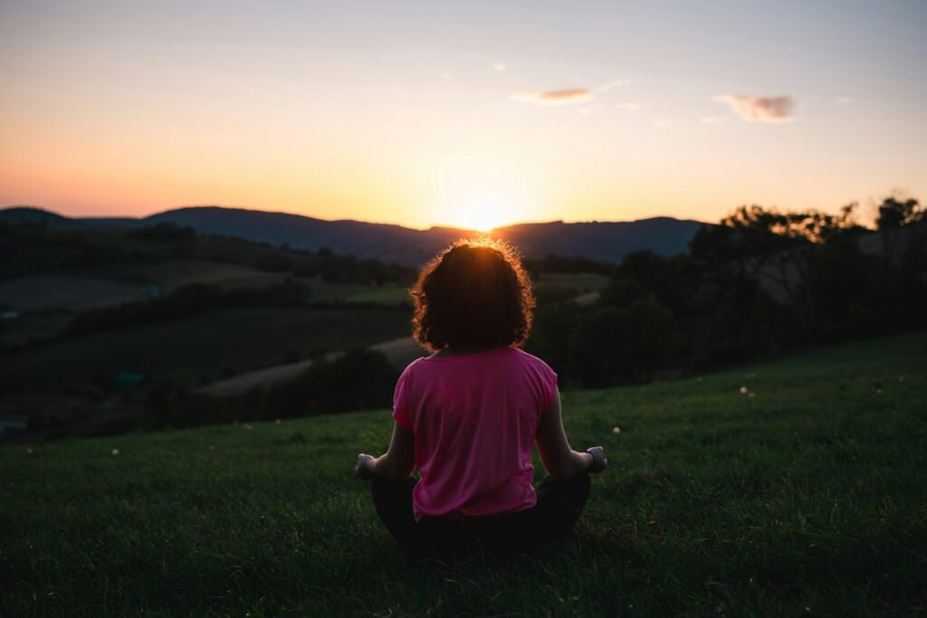 woman squatting in grass during golden hour