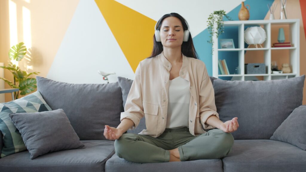 Woman meditating on couch with headphones on