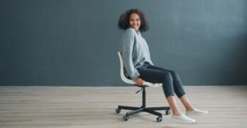 Young woman sitting on office chair, smiling at camera