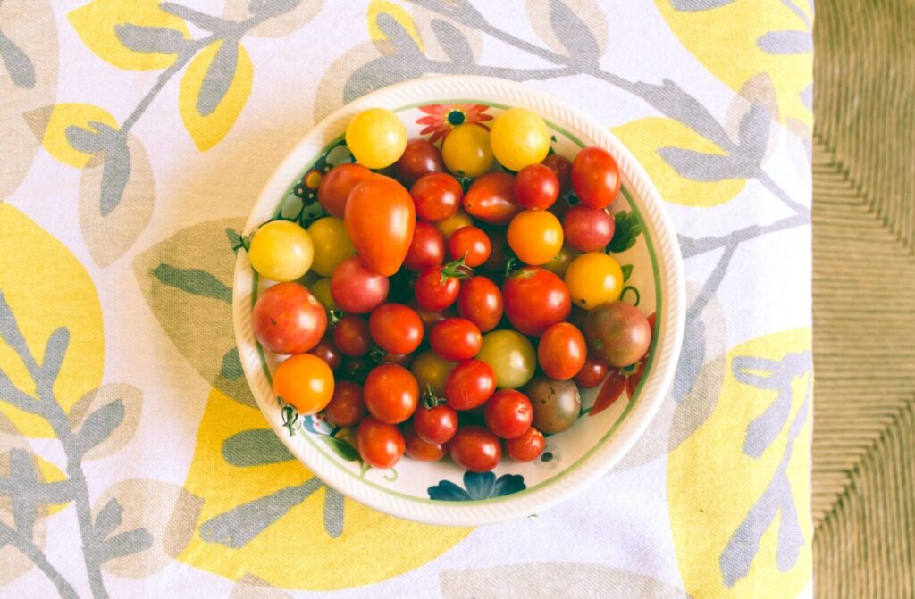 Vibrant assortment of cherry tomatoes in a bowl on a colorful floral tablecloth, ideal for healthy eating themes.