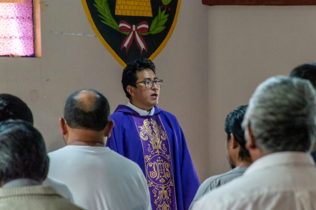 a priest standing in front of a group of people