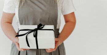 a woman in an apron holding a wrapped present